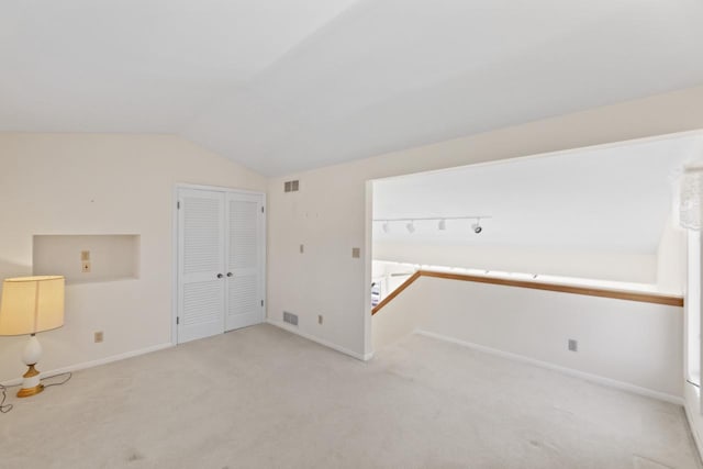 bonus room with baseboards, visible vents, lofted ceiling, and light carpet