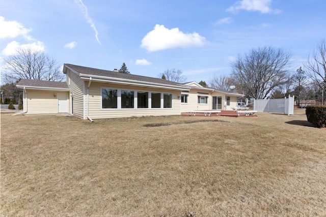 rear view of house featuring a deck, a yard, and fence