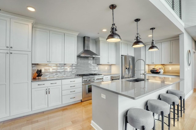 kitchen with a sink, light countertops, wall chimney exhaust hood, and stainless steel appliances