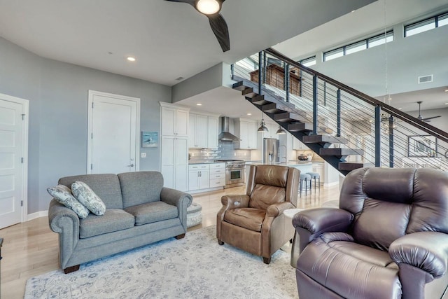 living room featuring stairway, baseboards, recessed lighting, ceiling fan, and light wood-type flooring