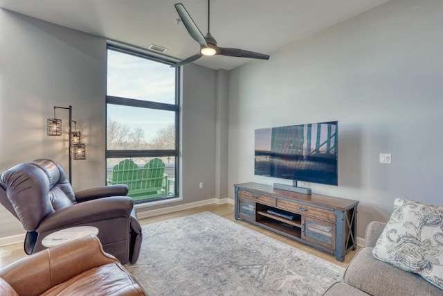 living room featuring visible vents, baseboards, ceiling fan, floor to ceiling windows, and wood finished floors