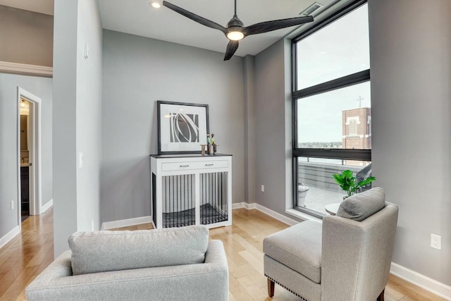 living area with ceiling fan, wood finished floors, visible vents, and baseboards