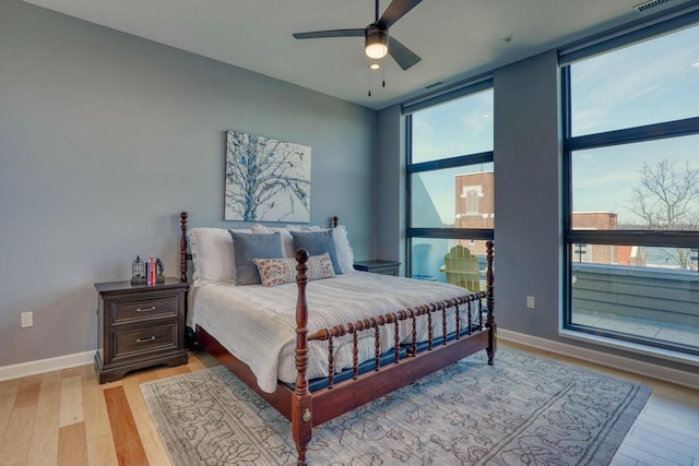 bedroom with a wall of windows, visible vents, baseboards, and light wood-style flooring