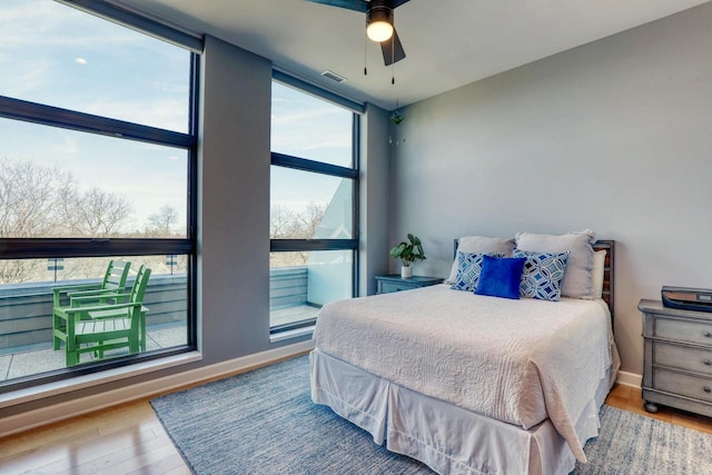 bedroom featuring expansive windows, baseboards, visible vents, and wood finished floors