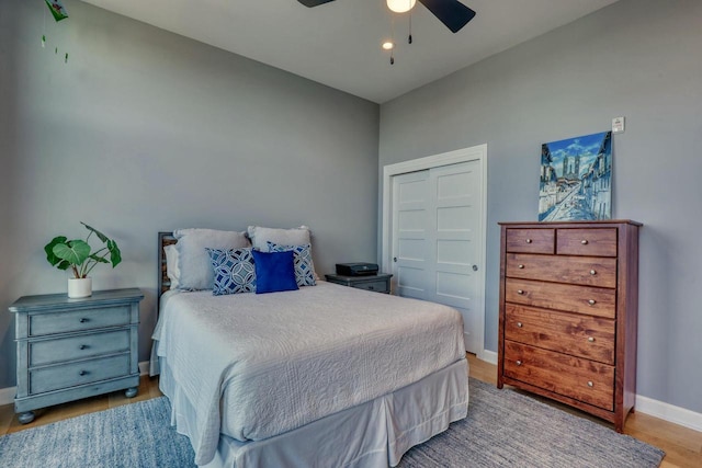 bedroom with ceiling fan, wood finished floors, a closet, and baseboards