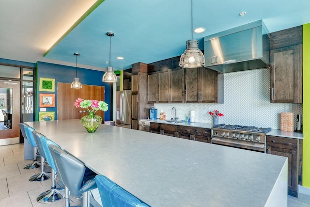 kitchen with light tile patterned floors, backsplash, appliances with stainless steel finishes, and wall chimney range hood