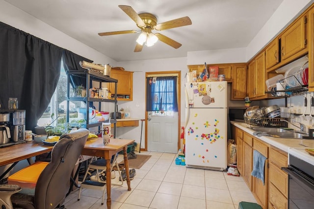 kitchen featuring a ceiling fan, freestanding refrigerator, a sink, light countertops, and brown cabinets