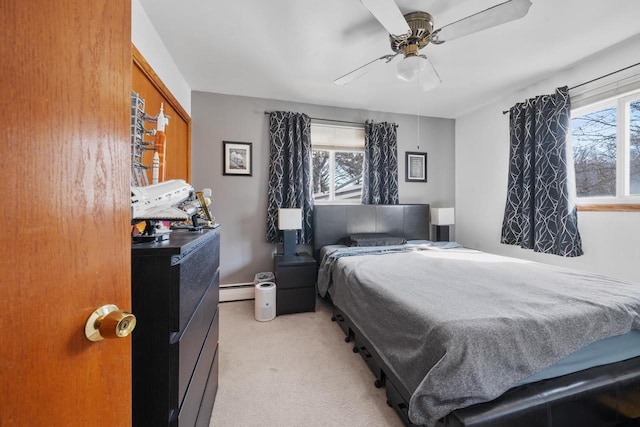 bedroom with multiple windows, light colored carpet, a baseboard radiator, and ceiling fan