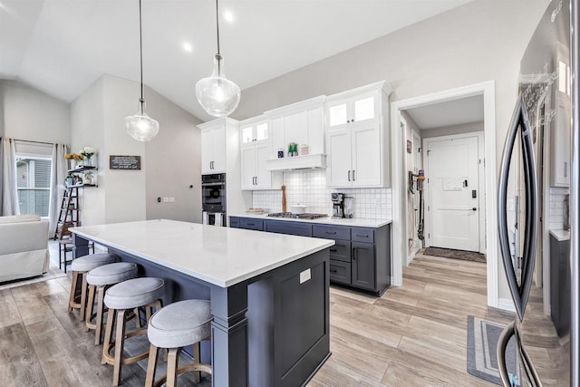 kitchen with a kitchen island, a breakfast bar, stainless steel appliances, white cabinets, and backsplash