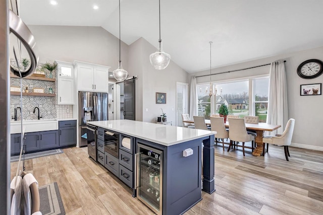 kitchen with light countertops, wine cooler, white cabinets, light wood-style floors, and stainless steel fridge