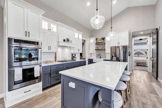 kitchen with open shelves, gray cabinetry, stainless steel appliances, white cabinets, and a center island