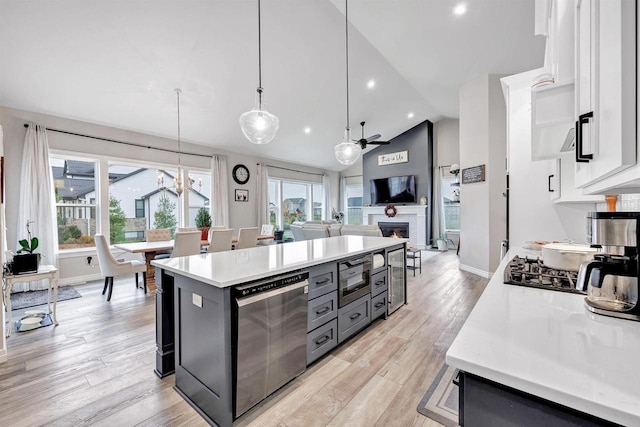 kitchen with built in microwave, light countertops, ceiling fan with notable chandelier, light wood-style floors, and white cabinetry