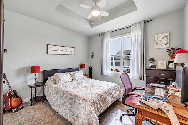 bedroom with a raised ceiling, carpet, and baseboards