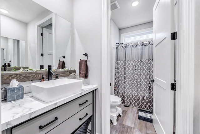 bathroom featuring visible vents, toilet, wood finished floors, a shower with shower curtain, and vanity