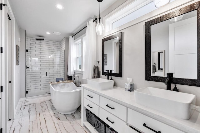 bathroom with a freestanding bath, a stall shower, a wealth of natural light, and a sink