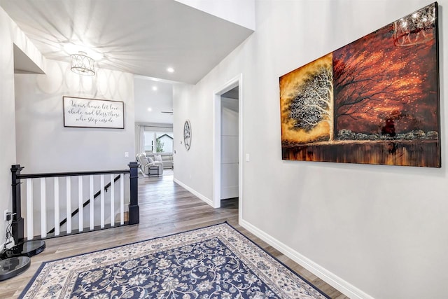 hallway featuring an upstairs landing, recessed lighting, baseboards, and wood finished floors