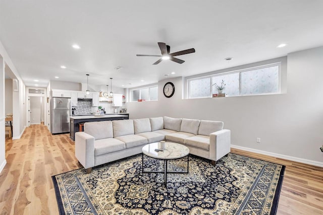 living area with recessed lighting, baseboards, light wood-type flooring, and ceiling fan