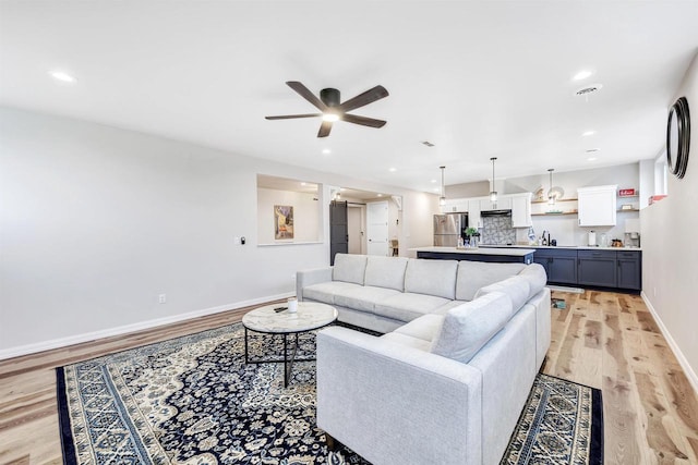 living area featuring recessed lighting, baseboards, light wood-type flooring, and ceiling fan