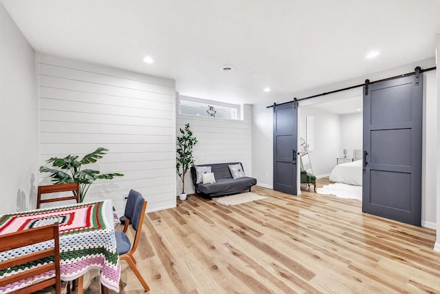 sitting room featuring a barn door, light wood-style flooring, recessed lighting, and visible vents