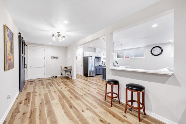 kitchen featuring recessed lighting, a kitchen breakfast bar, light wood-type flooring, and freestanding refrigerator