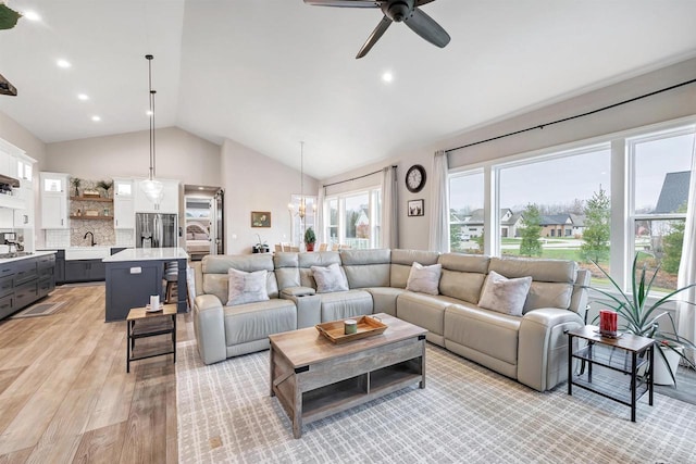 living area with recessed lighting, light wood finished floors, high vaulted ceiling, and ceiling fan with notable chandelier