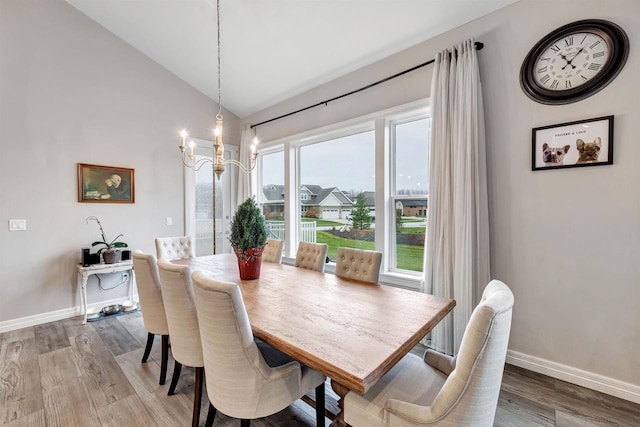 dining space with vaulted ceiling, baseboards, an inviting chandelier, and wood finished floors