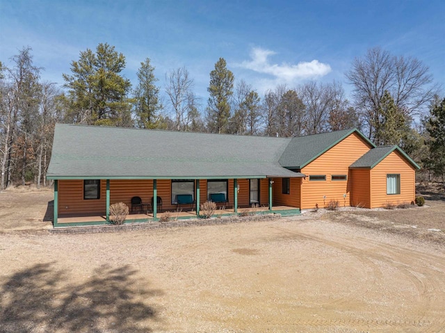 rustic home with log veneer siding, covered porch, driveway, and a shingled roof