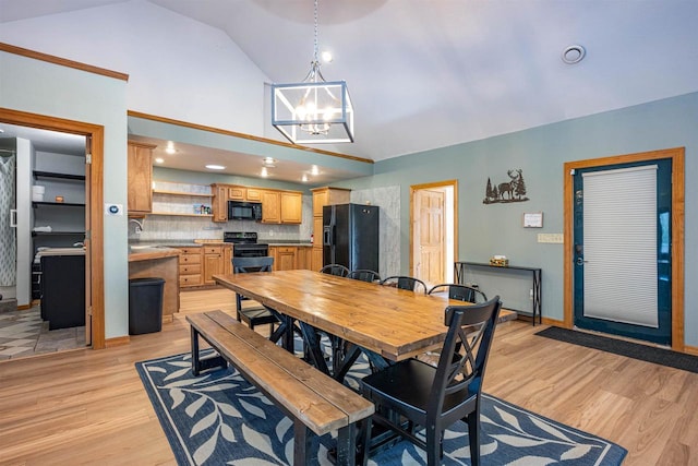 dining space featuring light wood-type flooring, baseboards, high vaulted ceiling, and a chandelier