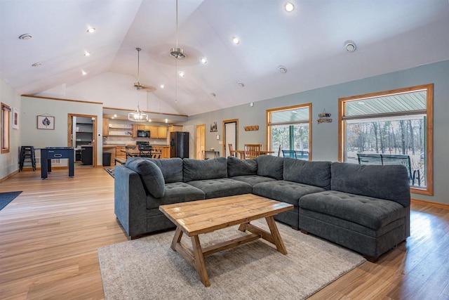 living area with baseboards, light wood finished floors, and high vaulted ceiling