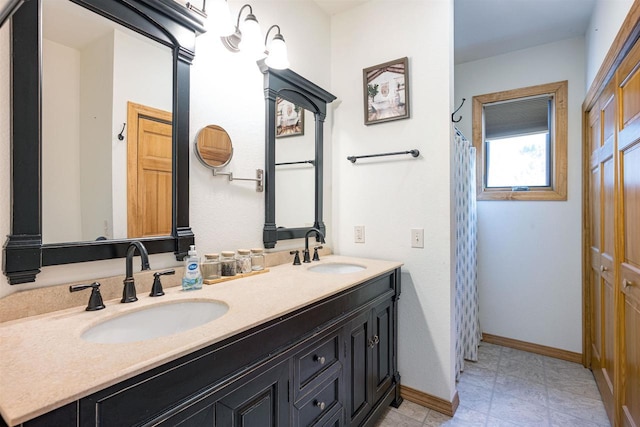 full bathroom with a shower with shower curtain, double vanity, baseboards, and a sink