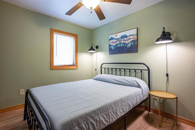 bedroom featuring baseboards, wood finished floors, and a ceiling fan