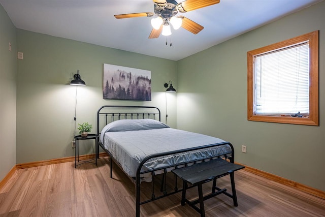 bedroom featuring a ceiling fan, baseboards, and wood finished floors