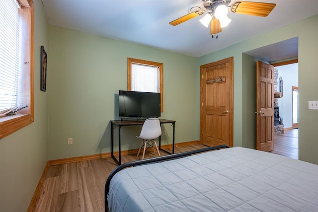 bedroom featuring ceiling fan, baseboards, and wood finished floors