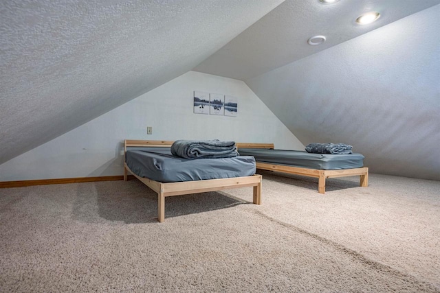 bedroom with lofted ceiling, carpet flooring, baseboards, and a textured ceiling