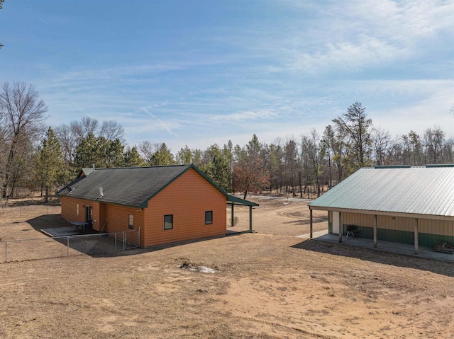 view of property exterior with faux log siding, a pole building, an outdoor structure, and fence