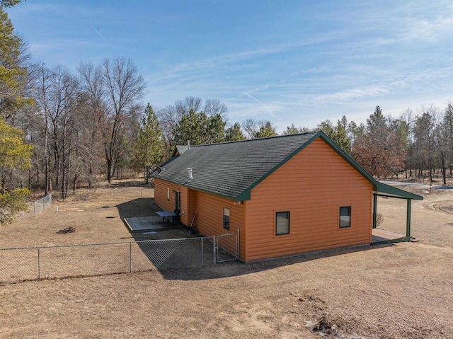 view of side of property featuring faux log siding, fence, and roof with shingles