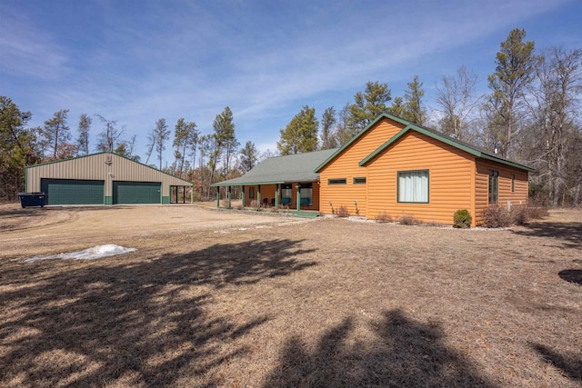 back of house with an outbuilding, faux log siding, a detached garage, and dirt driveway