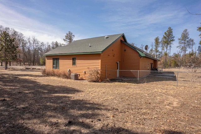 view of property exterior featuring faux log siding, central AC unit, and fence