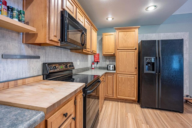 kitchen featuring open shelves, light wood-style flooring, black appliances, wood counters, and tasteful backsplash