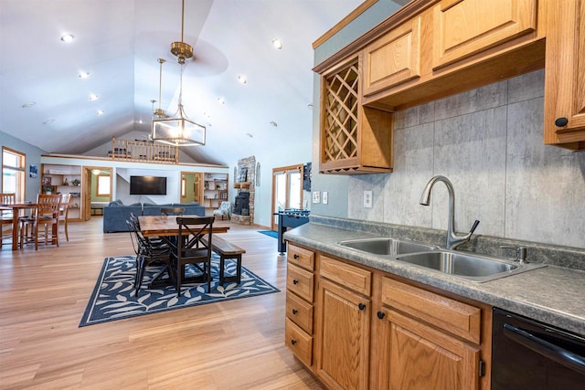 kitchen featuring decorative light fixtures, open floor plan, light wood-type flooring, black dishwasher, and a sink