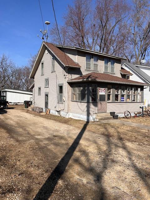 back of house featuring entry steps, a sunroom, and a shingled roof