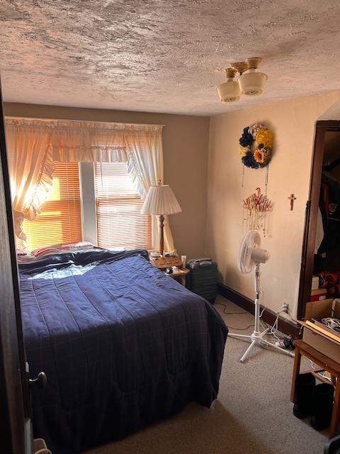 carpeted bedroom featuring baseboards and a textured ceiling