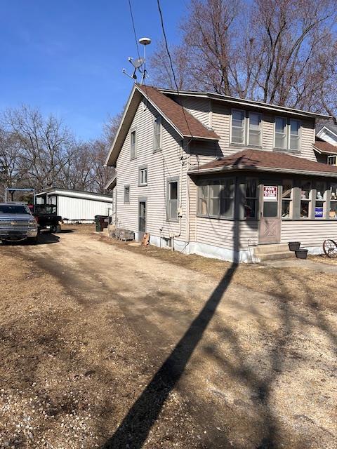 back of property with entry steps, a sunroom, and a shingled roof