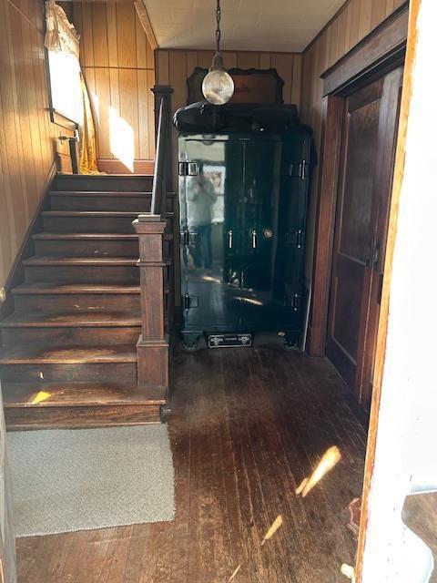 stairs featuring hardwood / wood-style floors and wooden walls