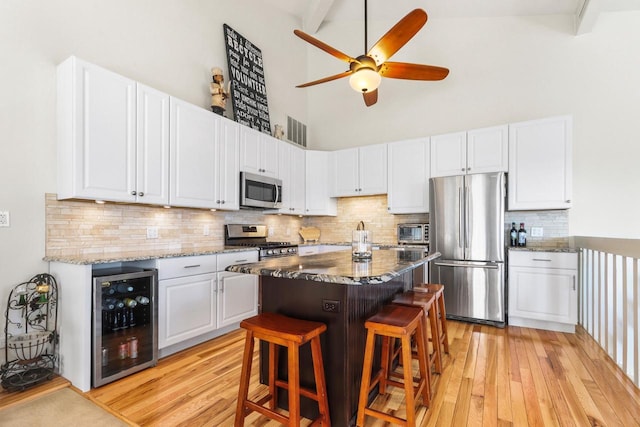 kitchen featuring light wood finished floors, visible vents, a center island, beverage cooler, and stainless steel appliances