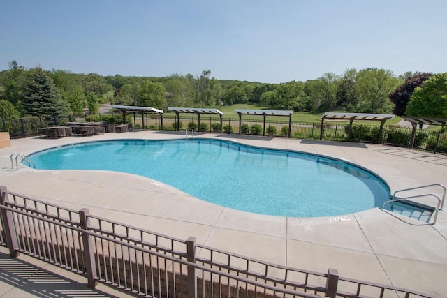 pool with a pergola, a patio, and fence