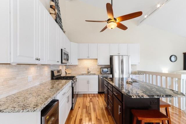 kitchen featuring ceiling fan, wine cooler, a breakfast bar, appliances with stainless steel finishes, and white cabinets