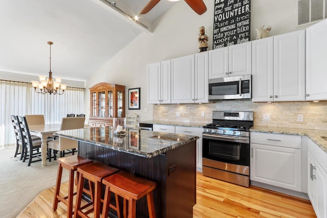 kitchen featuring decorative backsplash, white cabinets, visible vents, and stainless steel appliances