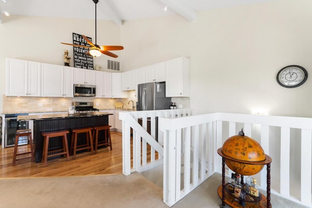 kitchen with a ceiling fan, visible vents, high vaulted ceiling, stainless steel appliances, and white cabinetry