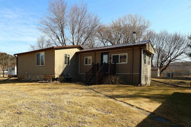 back of property featuring central AC unit, metal roof, a yard, and fence